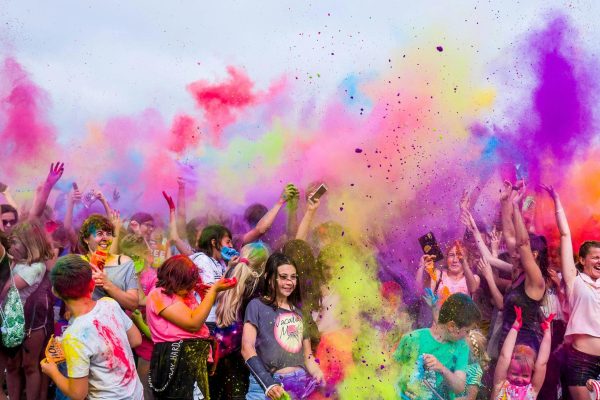 pexels-photo-1684187-1684187-1 A joyful crowd covered in vivid colors celebrates a festival outdoors with flying powder.